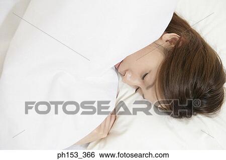 Stock Photograph - Close-up of a young woman sleeping on the bed. Fotosearch