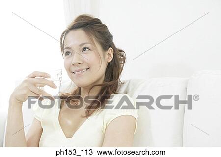 Close-up of a young woman smiling and holding a glass of water View Large Photo Image Stock Image - Close-up of a young woman smiling and holding a glass of water. Fotosearch