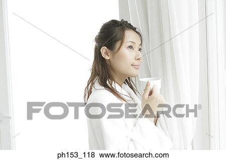 Close-up of a young woman standing and holding a cup of coffee View Large Photo Image Stock Photo - Close-up of a young woman standing and holding a cup of coffee. Fotosearch
