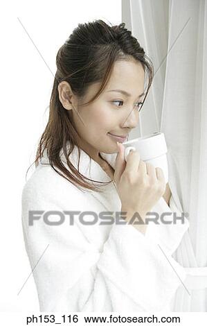 Stock Photograph - Close-up of a young woman standing and holding a cup of coffee. Fotosearch