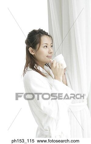 Close-up of a young woman standing and holding a cup of coffee View Large Photo Image Stock Photography - Close-up of a young woman standing and holding a cup of coffee. Fotosearch