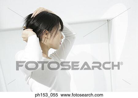 Close-up of a young woman tying her hair View Large Photo Image Stock Photography - Close-up of a young woman tying her hair. Fotosearch