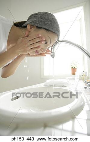 Close-up of a young woman washing her face over a bathroom sink View Large Photo Image Stock Image - Close-up of a young woman washing her face over a bathroom sink. Fotosearch