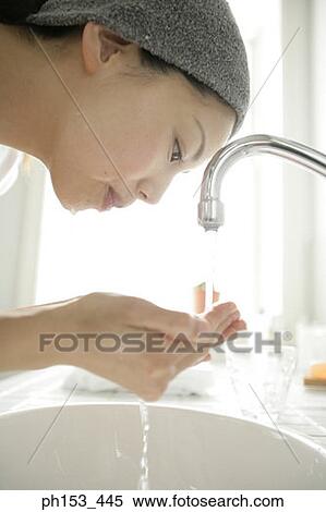 Close-up of a young woman washing her face over a bathroom sink View Large Photo Image Stock Photography - Close-up of a young woman washing her face over a bathroom sink. Fotosearch