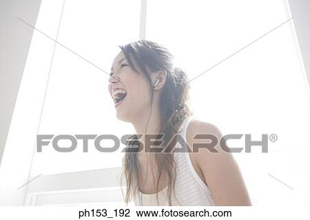 Close-up of a young woman wearing headphones and looking cheerful View Large Photo Image Stock Image - Close-up of a young woman wearing headphones and looking cheerful. Fotosearch