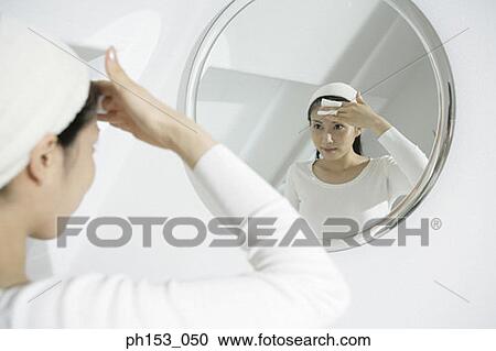 Close-up of a young woman wiping her forehead with a tissue paper in front of a mirror View Large Photo Image Stock Image - Close-up of a young woman wiping her forehead with a tissue paper in front of a mirror. Fotosearch