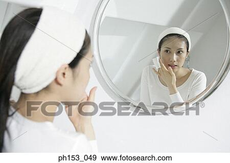Close-up of a young woman wiping her face with a tissue paper in front of a mirror View Large Photo Image Stock Photo - Close-up of a young woman wiping her face with a tissue paper in front of a mirror. Fotosearch