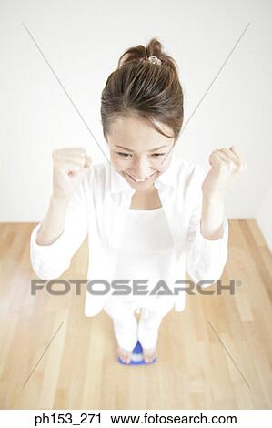 High angle view of a young woman standing on a weighing scale and making fists View Large Photo Image Stock Image - High angle view of a young woman standing on a weighing scale and making fists. Fotosearch