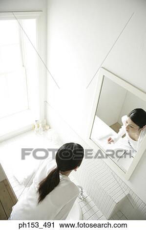 Stock Image - High angle view of a young woman looking in a mirror. Fotosearch