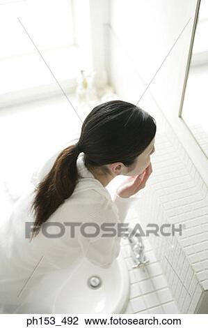High angle view of a young woman looking in a mirror View Large Photo Image Stock Image - High angle view of a young woman looking in a mirror. Fotosearch