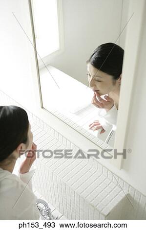 High angle view of a young woman looking in a mirror and touching her lips View Large Photo Image Stock Image - High angle view of a young woman looking in a mirror and touching her lips. Fotosearch