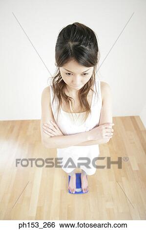 High angle view of a young woman standing on a weighing scale View Large Photo Image Stock Photograph - High angle view of a young woman standing on a weighing scale. Fotosearch