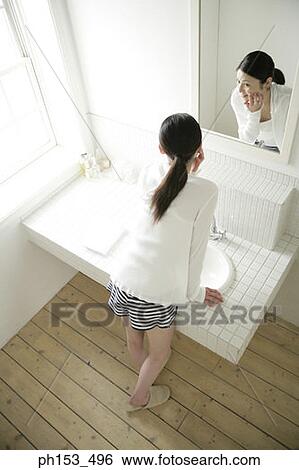 High angle view of a young woman looking in a mirror and touching her face View Large Photo Image Stock Photograph - High angle view of a young woman looking in a mirror and touching her face. Fotosearch
