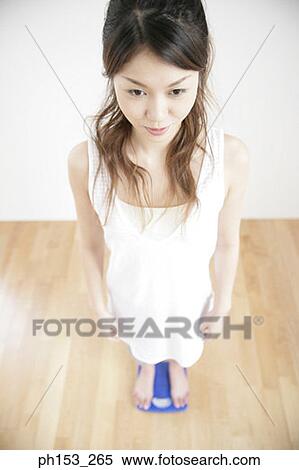 High angle view of a young woman standing on a weighing scale View Large Photo Image Stock Photography - High angle view of a young woman standing on a weighing scale. Fotosearch