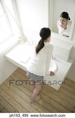 High angle view of a young woman standing in front of a mirror View Large Photo Image Stock Photography - High angle view of a young woman standing in front of a mirror. Fotosearch