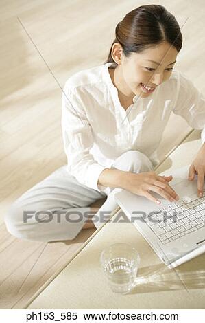 High angle view of a young woman sitting on the floor and using a laptop on a couch View Large Photo Image Stock Photography - High angle view of a young woman sitting on the floor and using a laptop on a couch. Fotosearch