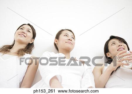 Low angle view of three young women leaning against a wall and smiling View Large Photo Image Stock Image - Low angle view of three young women leaning against a wall and smiling. Fotosearch