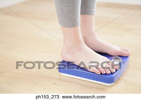 Low section view of a person standing on a weighing scale View Large Photo Image Stock Image - Low section view of a person standing on a weighing scale. Fotosearch
