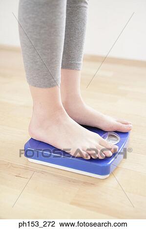 Low section view of a woman standing on a weighing scale View Large Photo Image Stock Image - Low section view of a woman standing on a weighing scale. Fotosearch
