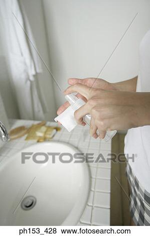 Mid section view of a woman spraying facial cleanser on a tissue paper View Large Photo Image Stock Photo - Mid section view of a woman spraying facial cleanser on a tissue paper. Fotosearch