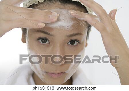 Portrait of a young woman applying soap on her forehead View Large Photo Image Stock Image - Portrait of a young woman applying soap on her forehead. Fotosearch
