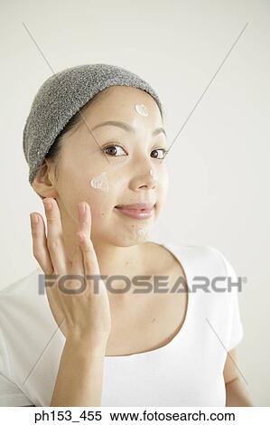 Portrait of a young woman applying moisturizer on her face View Large Photo Image Stock Photography - Portrait of a young woman applying moisturizer on her face. Fotosearch
