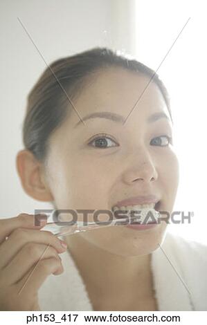 Stock Photo - Portrait of a young woman brushing her teeth. Fotosearch