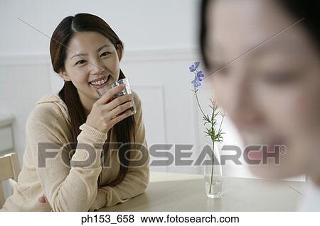 Portrait of a young woman drinking black tea and smiling with her sister View Large Photo Image Stock Photo - Portrait of a young woman drinking black tea and smiling with her sister. Fotosearch
