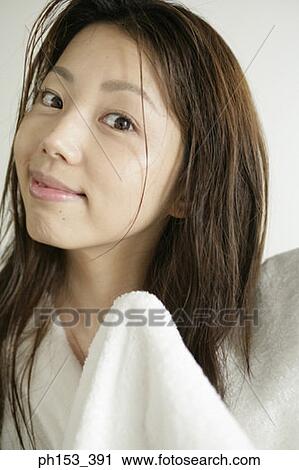 Stock Image - Portrait of a young woman drying her hair with a towel and smiling. Fotosearch
