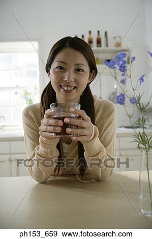 Portrait of a young woman holding a glass of black tea View Large Photo Image Stock Photo - Portrait of a young woman holding a glass of black tea. Fotosearch