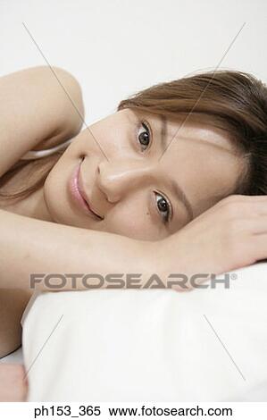Stock Photography - Portrait of a young woman lying on the bed and smiling. Fotosearch