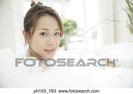 Portrait of a young woman relaxing in a bubble bath and smiling View Large Photo Image Stock Image - Portrait of a young woman relaxing in a bubble bath and smiling. Fotosearch