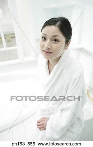 Stock Photography - Portrait of a young woman sitting near a bathtub and smiling. Fotosearch