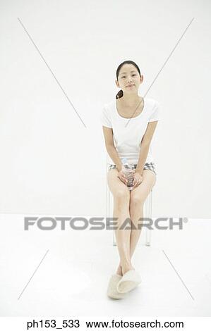 Portrait of a young woman sitting on a chair and holding a water bottle View Large Photo Image Stock Image - Portrait of a young woman sitting on a chair and holding a water bottle. Fotosearch