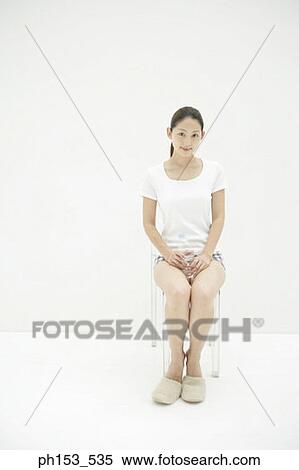 Portrait of a young woman sitting on a chair and holding a water bottle View Large Photo Image Stock Photography - Portrait of a young woman sitting on a chair and holding a water bottle. Fotosearch