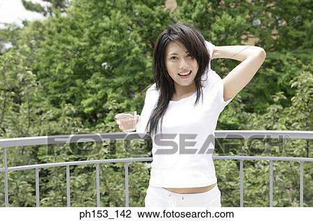 Portrait of a young woman smiling and holding a glass of water View Large Photo Image Stock Image - Portrait of a young woman smiling and holding a glass of water. Fotosearch