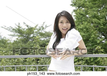 Portrait of a young woman smiling and holding a glass of water View Large Photo Image Stock Image - Portrait of a young woman smiling and holding a glass of water. Fotosearch
