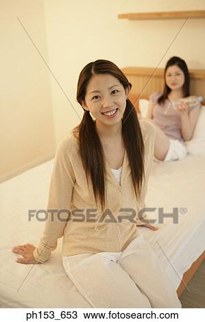 Portrait of a young woman smiling with her sister sitting behind her View Large Photo Image Stock Image - Portrait of a young woman smiling with her sister sitting behind her. Fotosearch
