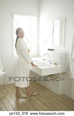 Portrait of a young woman standing near a bathroom sink and smiling View Large Photo Image Stock Photo - Portrait of a young woman standing near a bathroom sink and smiling. Fotosearch