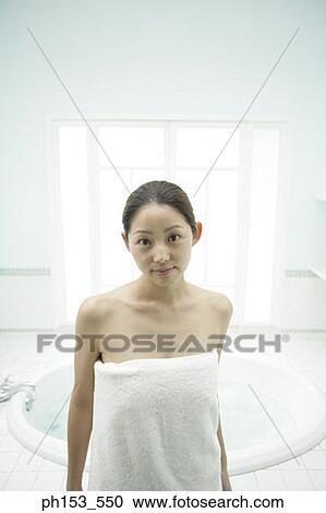 Portrait of a young woman wrapped in a towel and standing in the bathroom View Large Photo Image Stock Image - Portrait of a young woman wrapped in a towel and standing in the bathroom. Fotosearch
