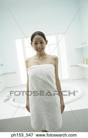 Portrait of a young woman wrapped in a towel and standing in the bathroom View Large Photo Image Stock Photo - Portrait of a young woman wrapped in a towel and standing in the bathroom. Fotosearch