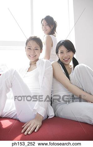 Portrait of three young women sitting on a couch and smiling View Large Photo Image Stock Image - Portrait of three young women sitting on a couch and smiling. Fotosearch