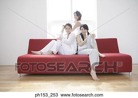 Portrait of three young women sitting on a couch and smiling View Large Photo Image Stock Image - Portrait of three young women sitting on a couch and smiling. Fotosearch