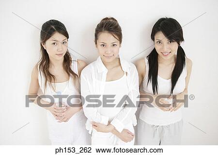 Portrait of three young women standing against a wall View Large Photo Image Stock Image - Portrait of three young women standing against a wall. Fotosearch