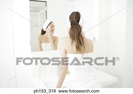 Rear view of a young woman cleaning her face with a tissue paper in the bathroom View Large Photo Image Stock Photo - Rear view of a young woman cleaning her face with a tissue paper in the bathroom. Fotosearch