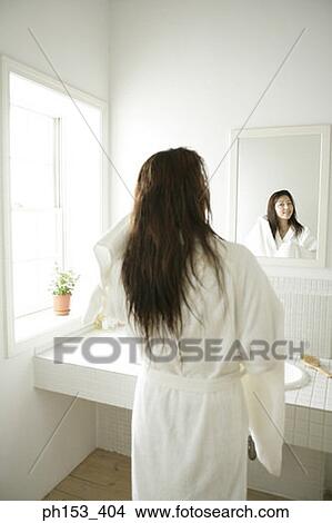 Rear view of a young woman drying her hair with a towel in front of a mirror View Large Photo Image Picture - Rear view of a young woman drying her hair with a towel in front of a mirror. Fotosearch