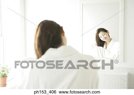 Rear view of a young woman drying her hair with a towel in front of a mirror View Large Photo Image Stock Photograph - Rear view of a young woman drying her hair with a towel in front of a mirror. Fotosearch