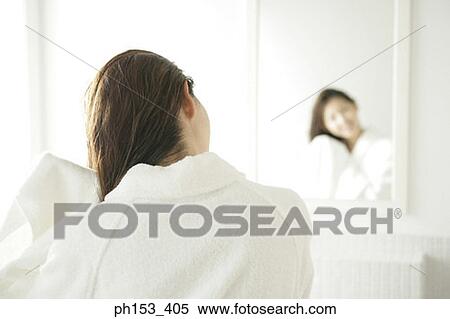 Rear view of a young woman drying her hair with a towel in front of a mirror View Large Photo Image Stock Photography - Rear view of a young woman drying her hair with a towel in front of a mirror. Fotosearch
