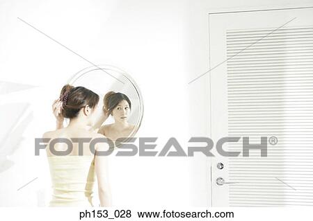 Rear view of a young woman looking at her hair bun in a mirror View Large Photo Image Stock Photo - Rear view of a young woman looking at her hair bun in a mirror. Fotosearch