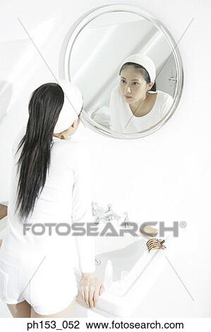 Rear view of a young woman looking in a mirror View Large Photo Image Stock Image - Rear view of a young woman looking in a mirror. Fotosearch